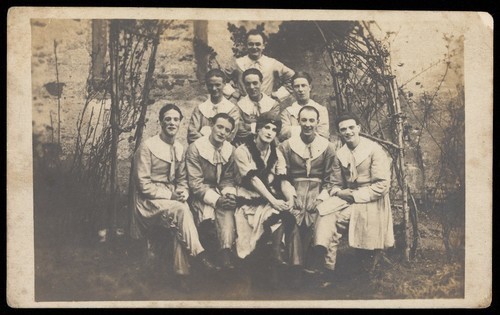 Download the full-sized image of Concert party performers, one in drag, pose for a group portrait. Photographic postcard, 191-.