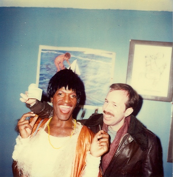 Download the full-sized image of A Photograph of Marsha P. Johnson Wearing a White Feathered Shirt, Posing with Another Person with Their Arm Around Her