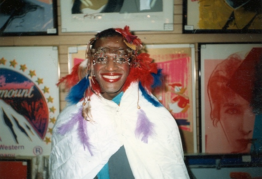 Download the full-sized image of A Photograph of Marsha P. Johnson Wearing a Feather Headpiece and Draped in a Cloak