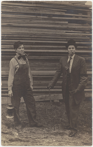 Download the full-sized image of Male impersonators in front of stack of lumber
