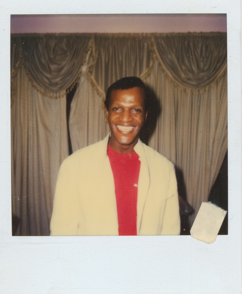 Download the full-sized image of A Photograph of Marsha P. Johnson Smiling in a White Button Up Over a Red Shirt